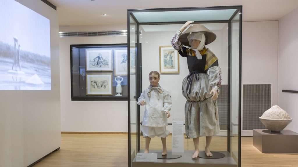 Un mannequin adulte et un mannequin enfant présentés dans une vitrine avec des vêtements traditionnels