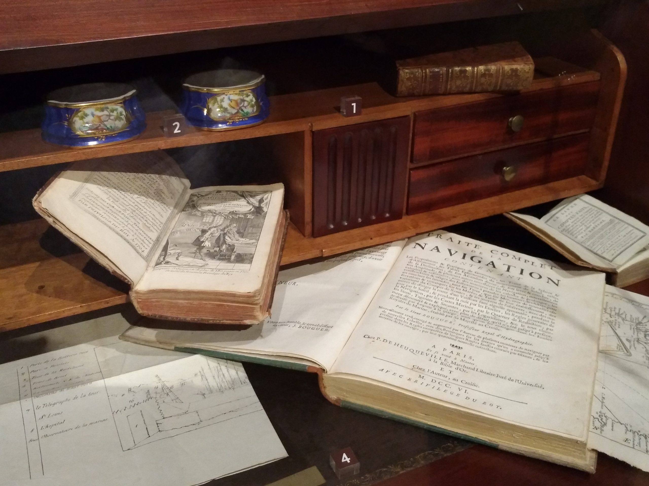 Zoom sur la vitrine du logement montrant un bureau ancien avec des livres ouverts.